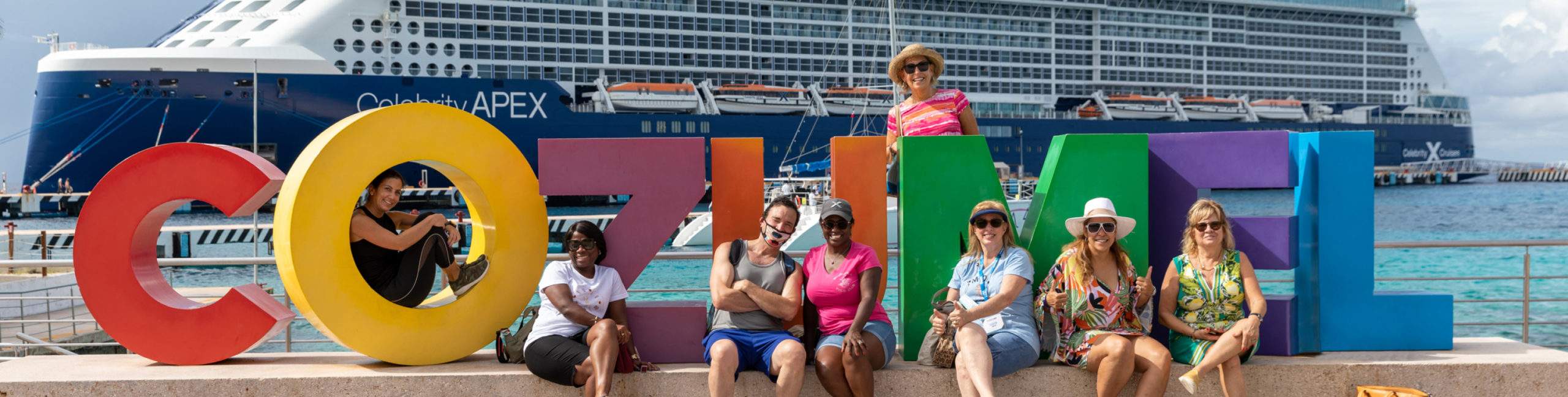 Travelers sitting around big letters that spell Cozumel