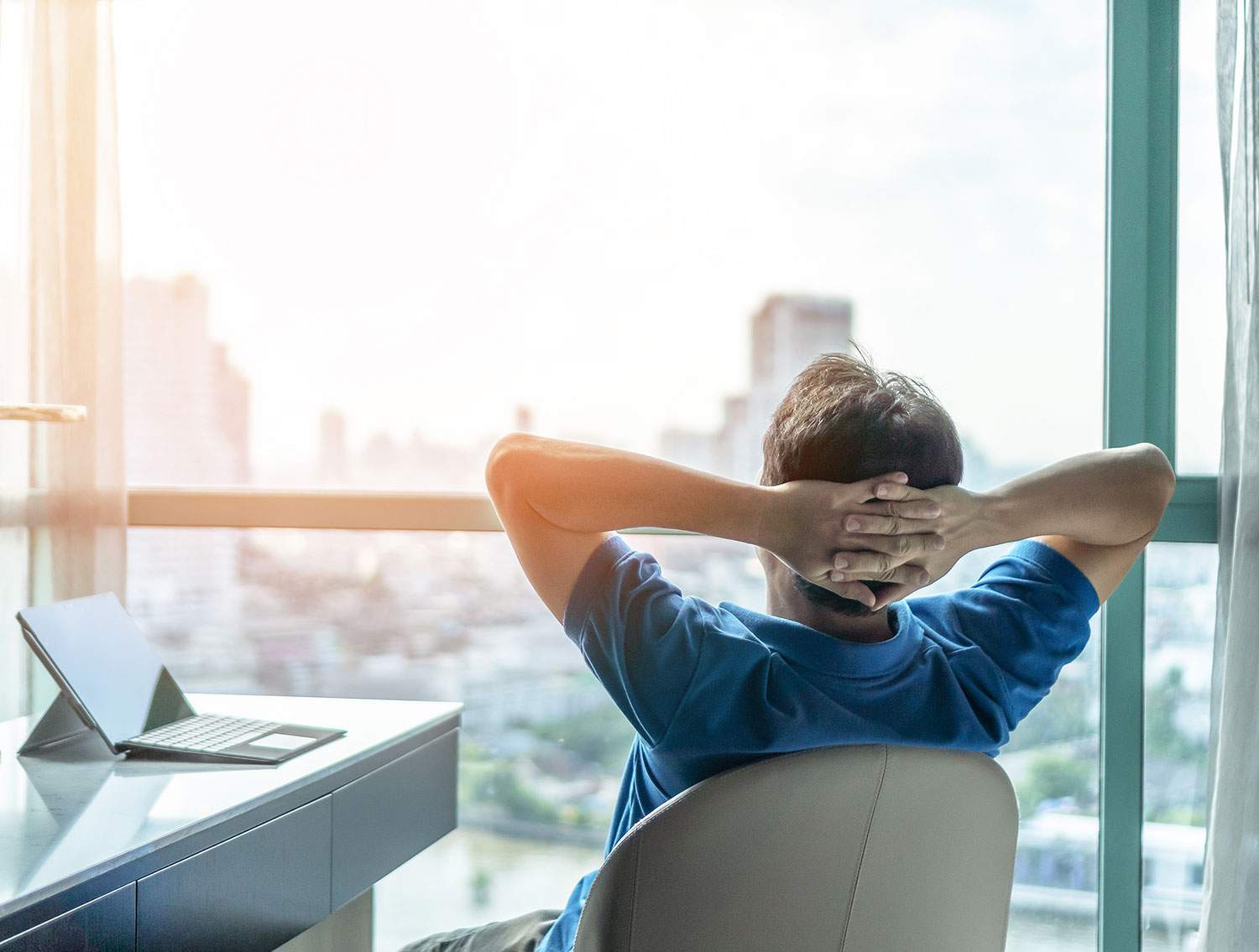 Man sitting at desk, looking out window at ocean, wondering: "How much does a travel advisor make?"