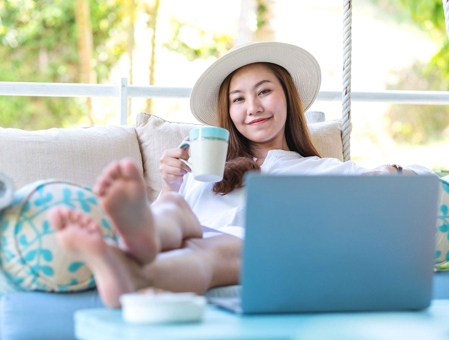Woman with her feet up by her laptop, enjoying her travel job -- how do you become a travel advisor?