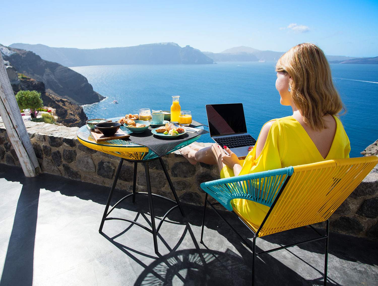 Woman working on laptop by ocean view - travel agent vs travel agency owner, what's the difference?