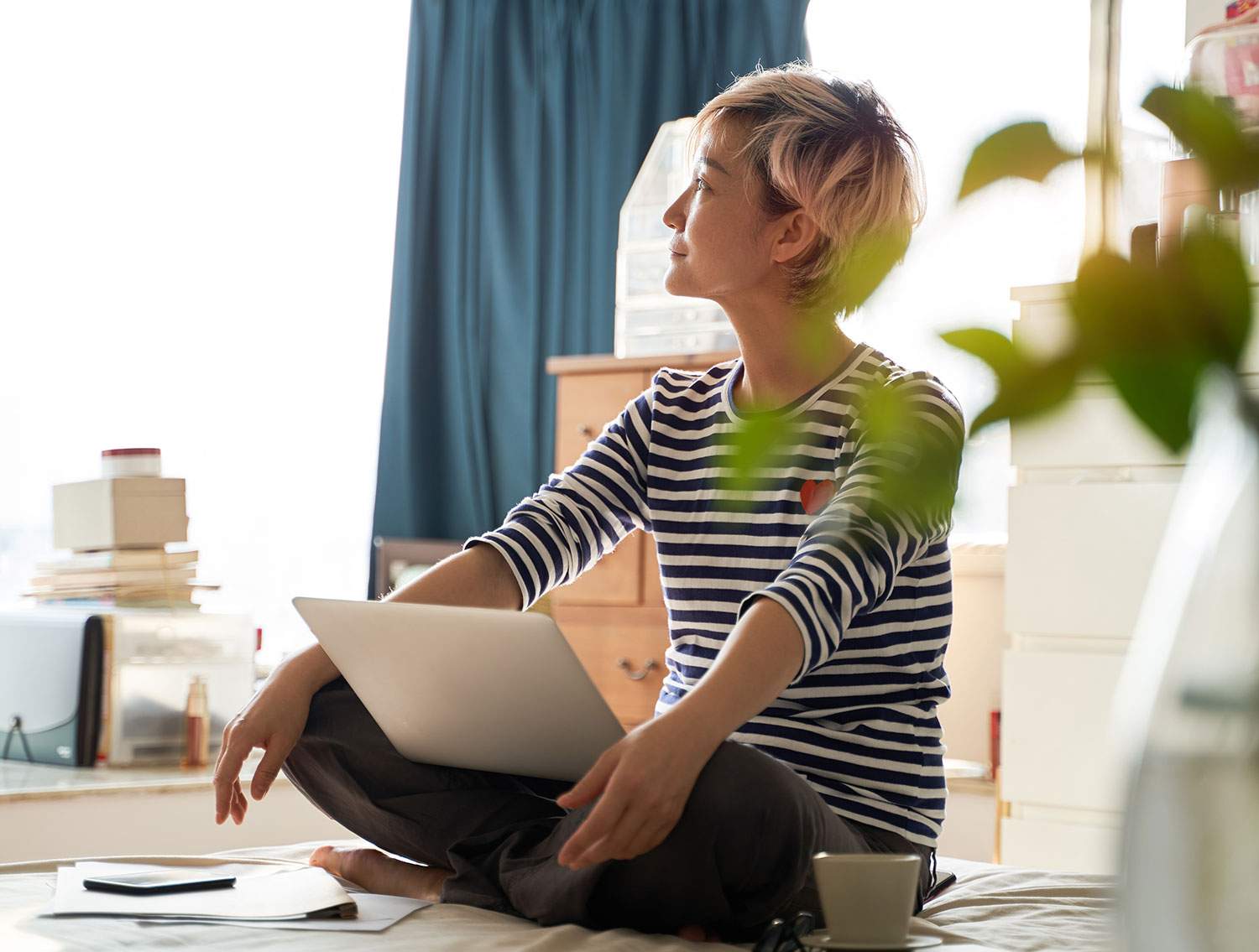 Woman sitting with laptop gazing at sunny apartment - discover part time remote travel agent jobs