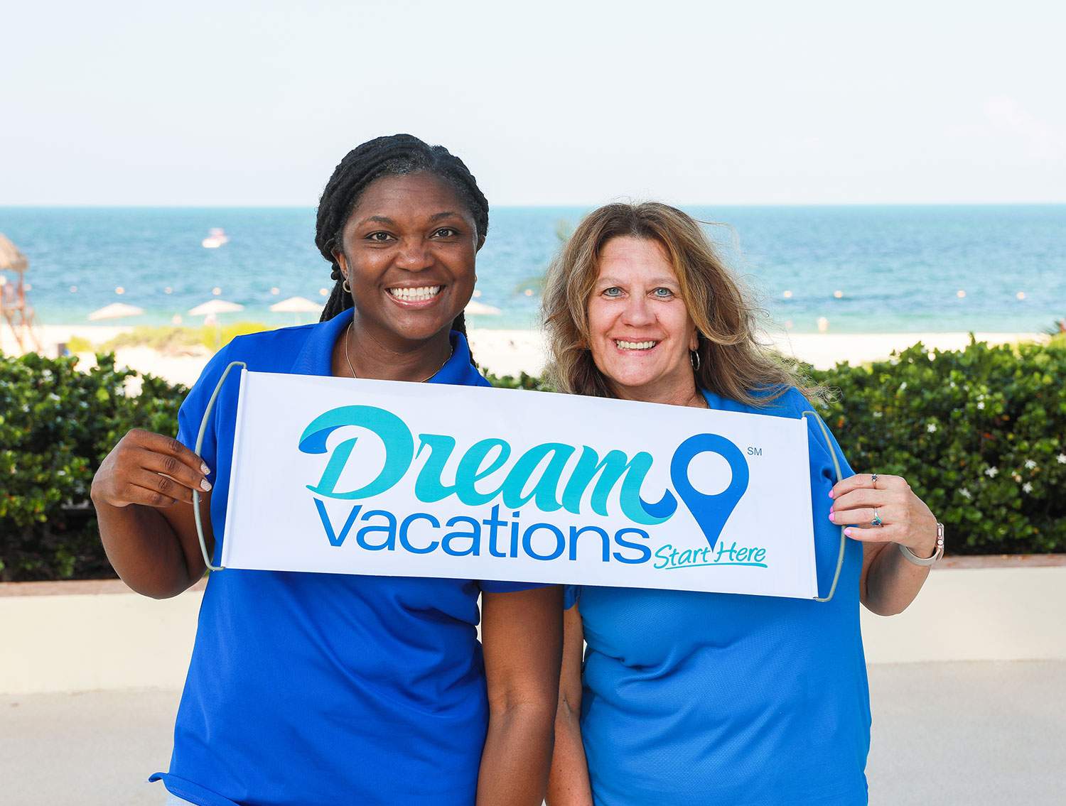 agents pose with dream vacations sign on beach
