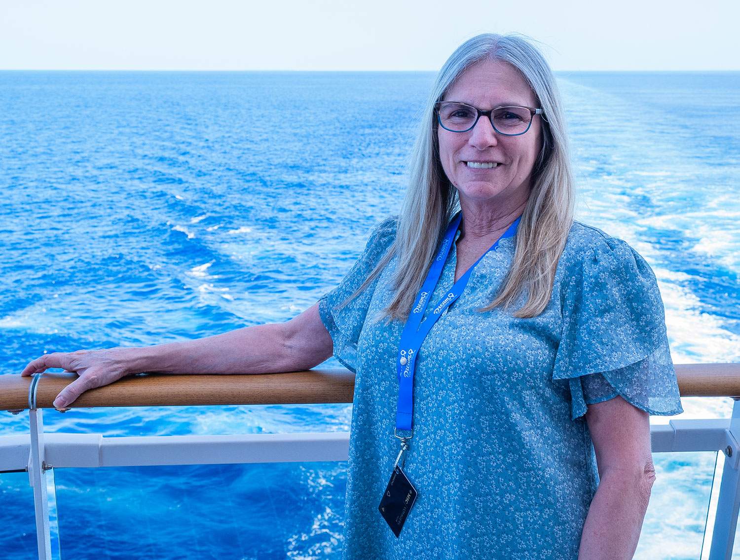 A woman stands on a cruise ship under a clear blue sky.