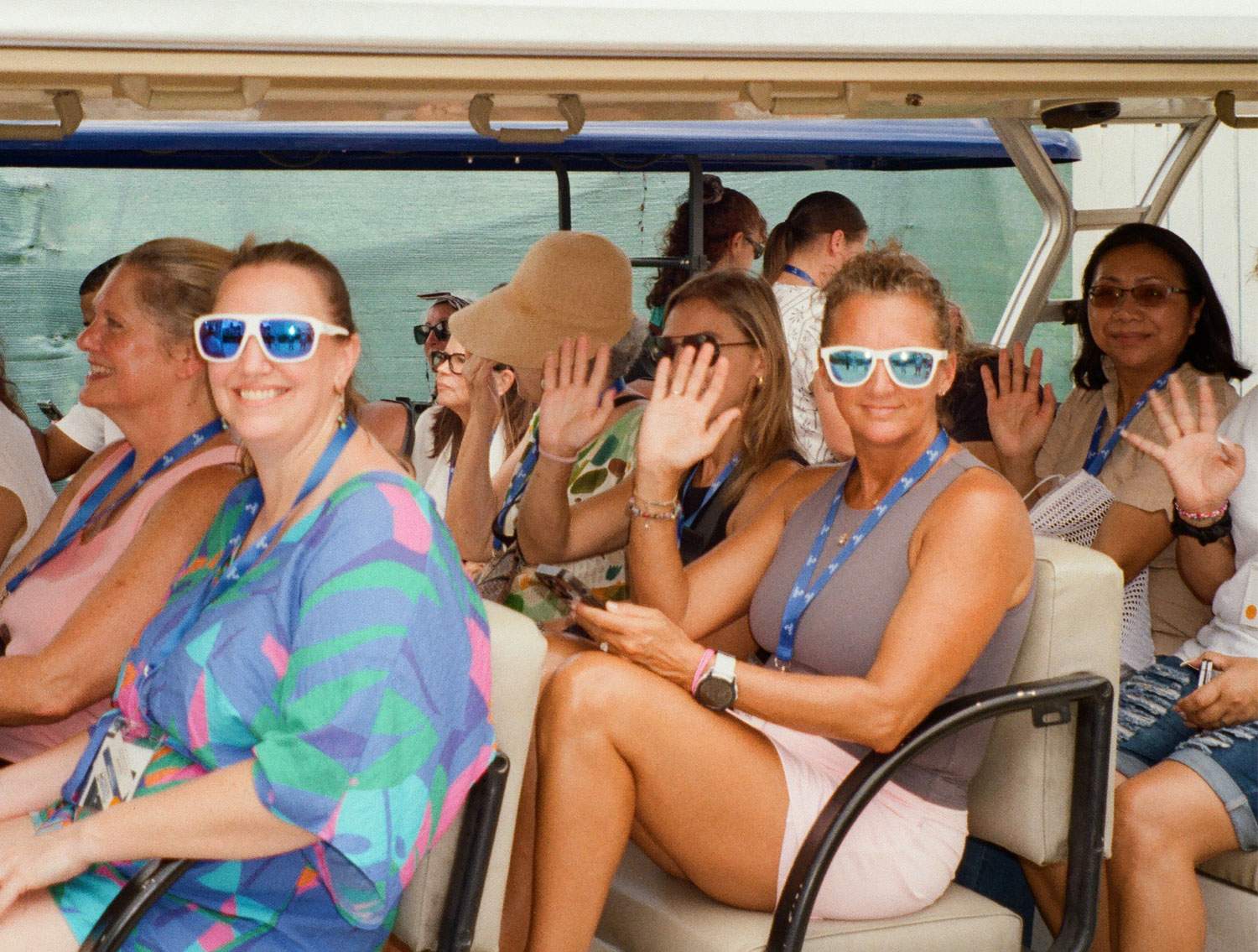 A group of women wearing sunglasses smiles together on a boat.